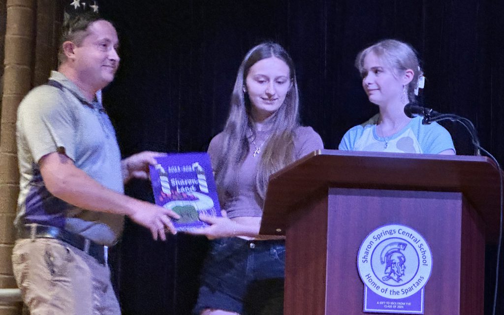teacher receives yearbook from two students
