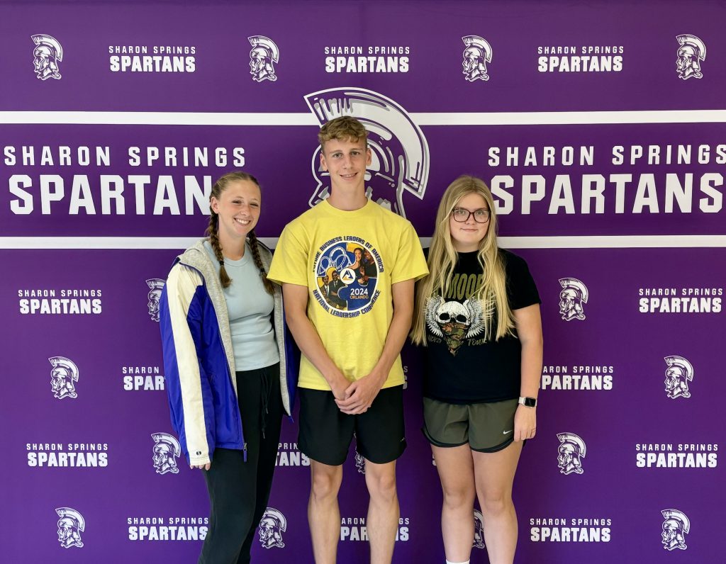 two boys and a girl in front of the Spartan backdrop