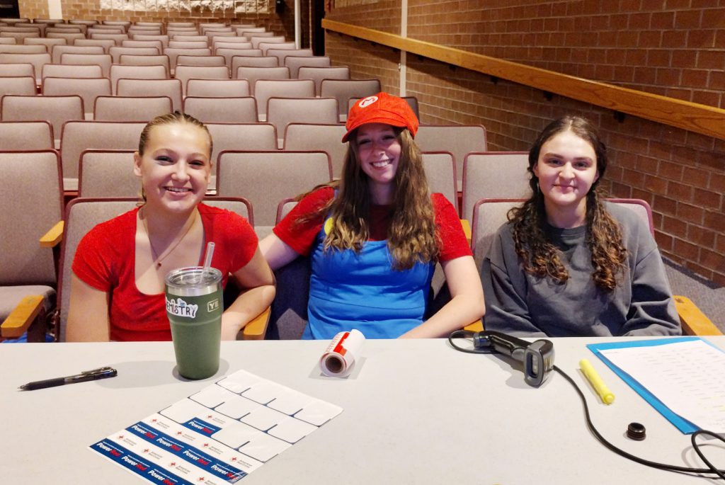 three girls work at a sign in table