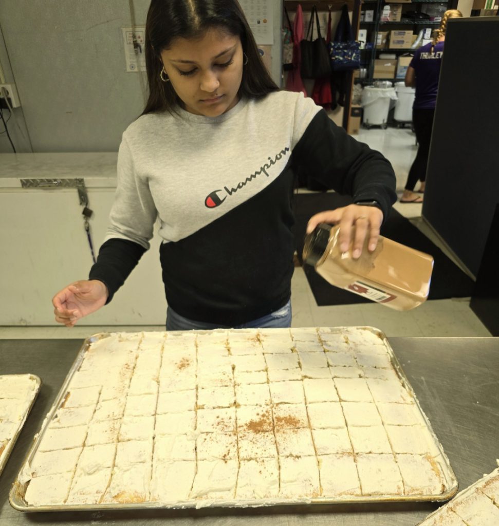 girl sprinkles cinnamon on a cake