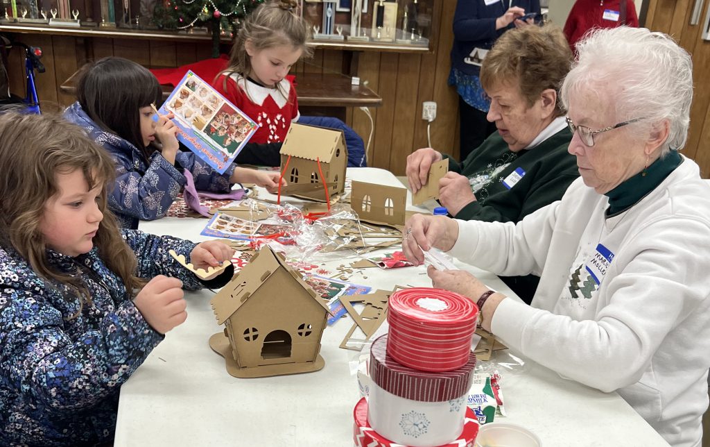 children and senior citizens work on gingerbread house craft together