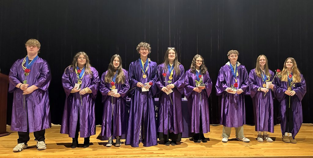 group of students dressed in blue gowns hold candles