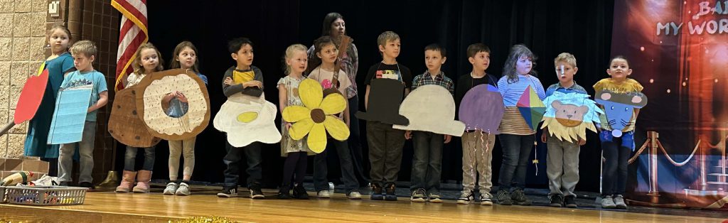 Kindergarteners dress as alphabet items on stage