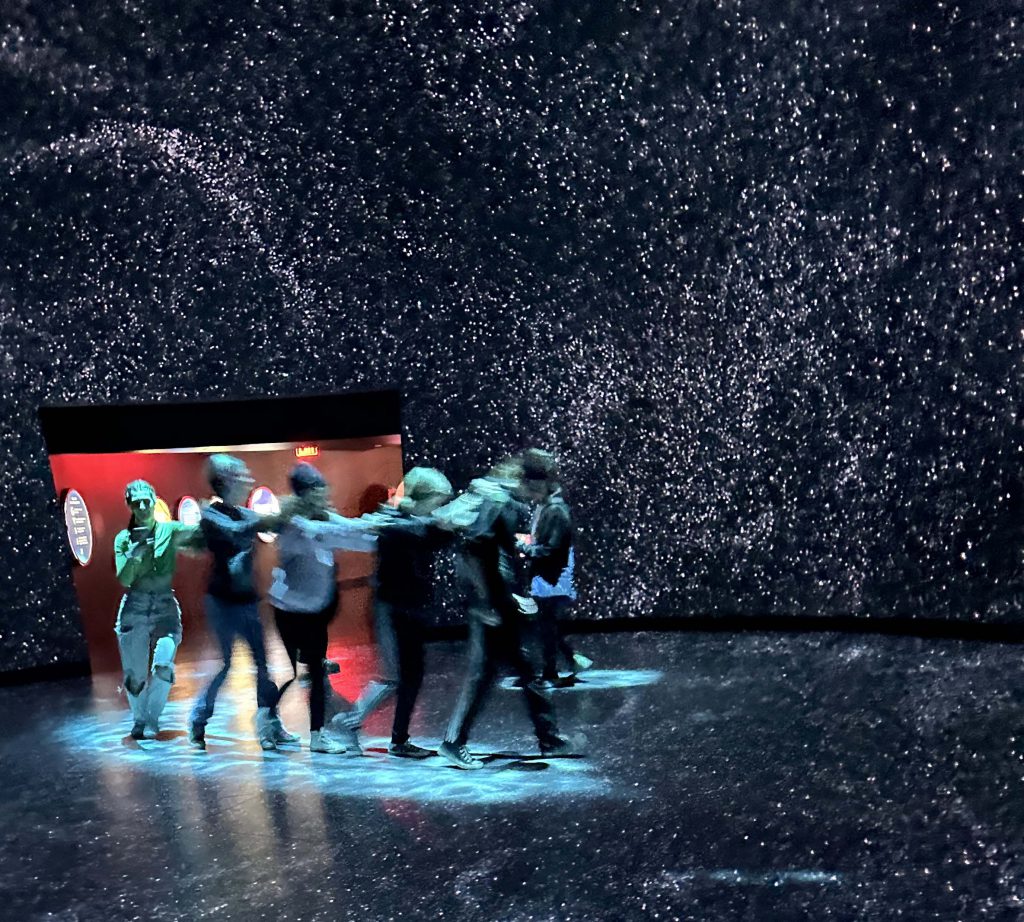 group of student explore the museum immersive exhibit with a night sky